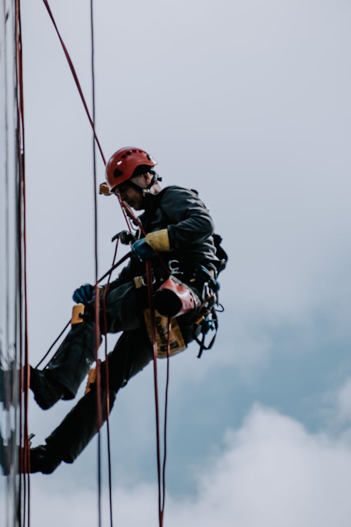 Professional worker rappelling down a building facade for maintenance.